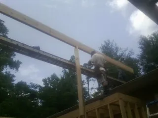 Carpenter setting a ridge beam over a new addition frame — Ice Dam Removal by Roofing Brothers in Greycliff