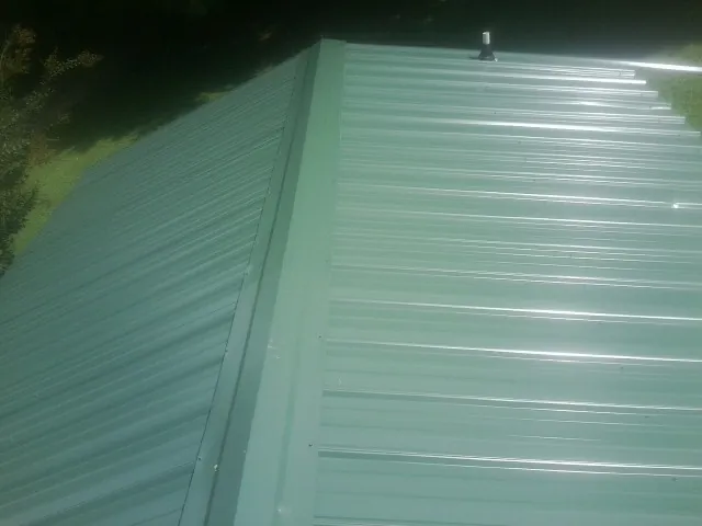 New green metal panels meeting at the ridge of a roof — Flat Roof Repair work by our crew in Greycliff
