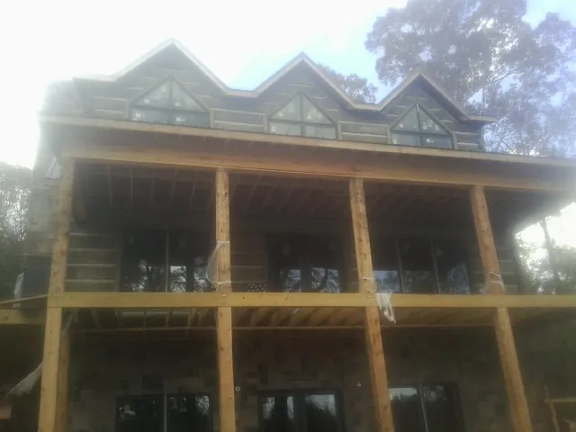Dormers and porch framing on a large log home under construction — Roof Coating work by our crew in Greycliff