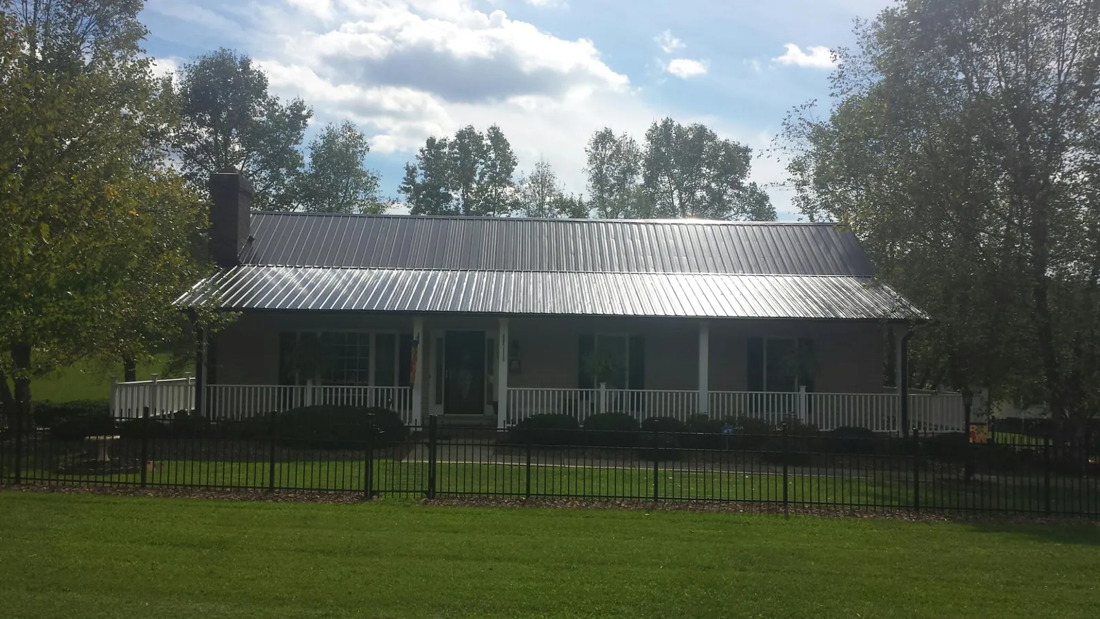 Gray metal roof on a brick ranch with a full width front porch — Gutter Guard Installation work by our crew in Greycliff