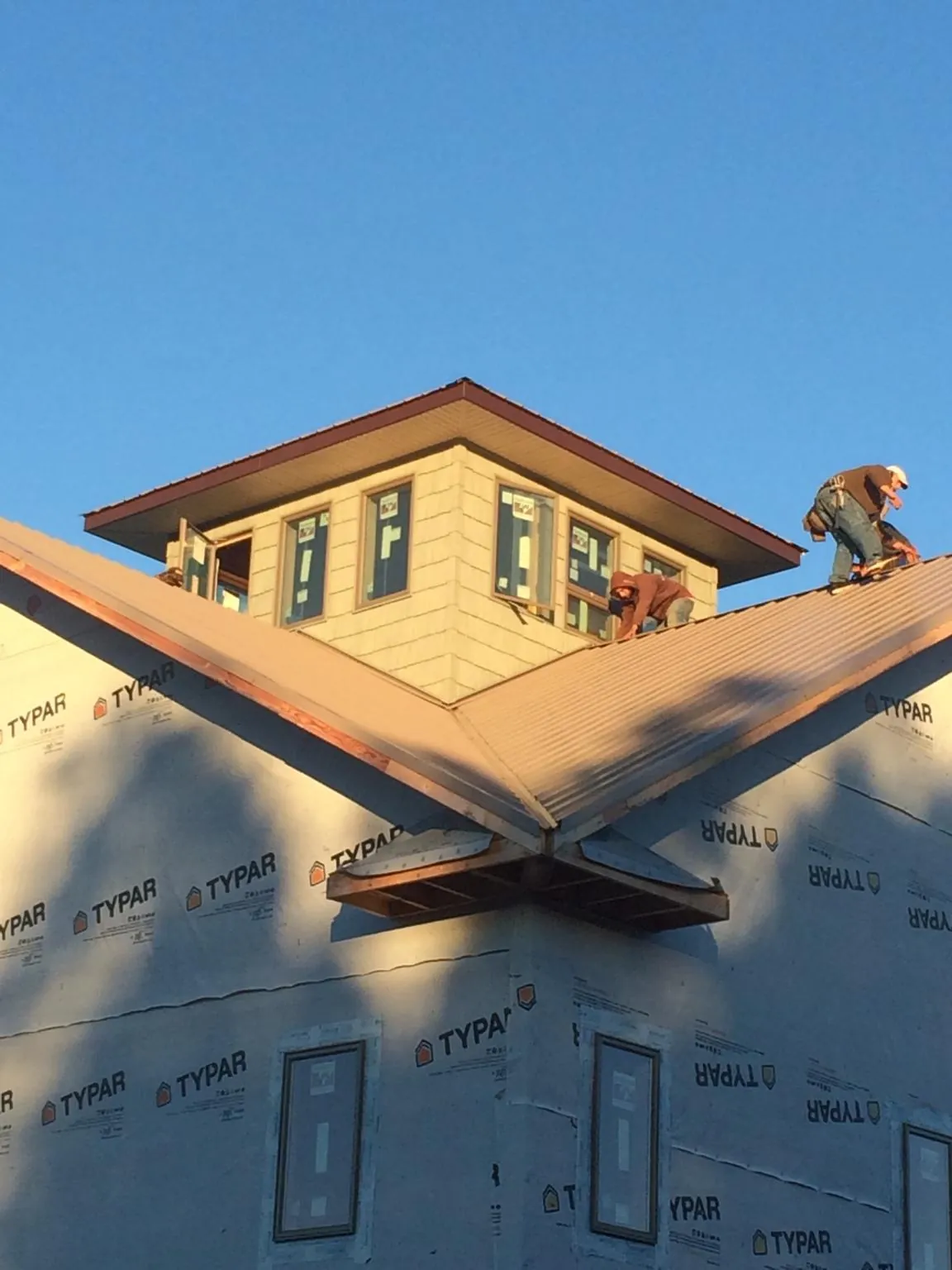 Roofers working around a rooftop cupola on a new metal roof at sunset — Roof Waterproofing in Greycliff by Roofing Brothers
